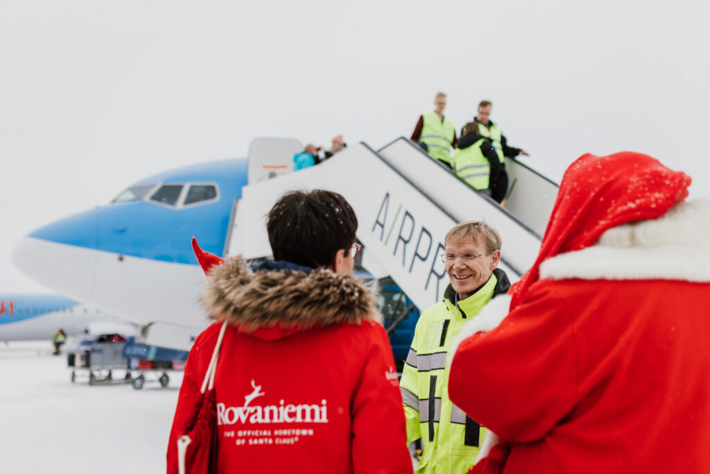 Joulupukki ja Sanna Kärkkäinen juttelevat miehen kanssa lentokoneen vierellä